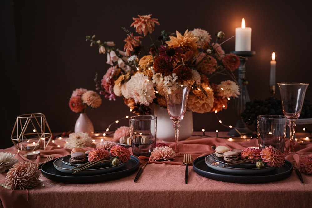 a table topped with plates and a vase filled with flowers