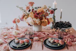 Close-up of a beautifully arranged table with pink roses, golden candles, and delicate pastries