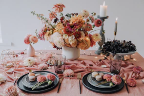 Close-up of a beautifully arranged table with pink roses, golden candles, and delicate pastries