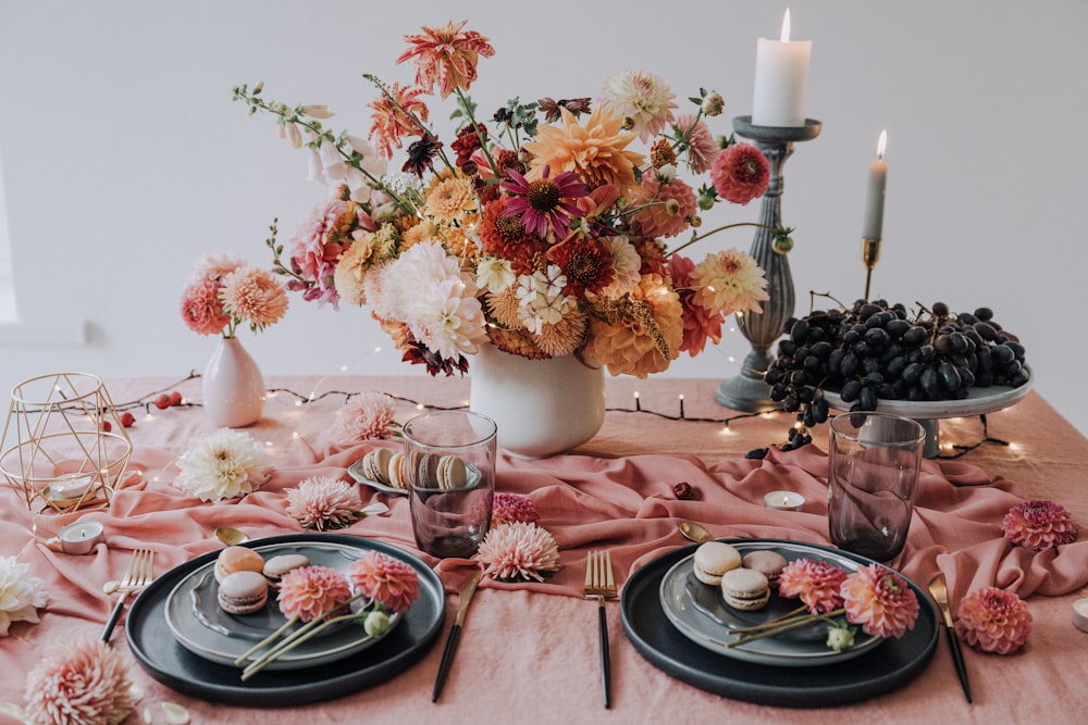 a table topped with plates and a vase filled with flowers