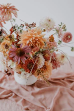 A vibrant bouquet of autumn-hued flowers arranged with delicate petals in a cozy Singaporean home setting.