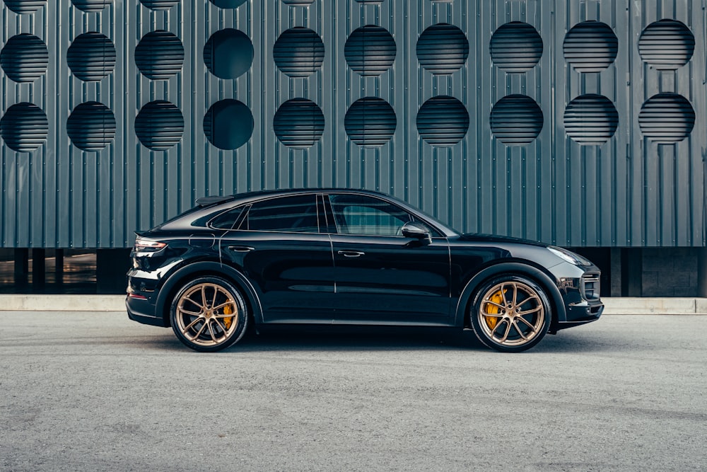 a black porsche cayen is parked in front of a building