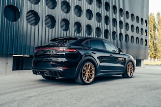 a black porsche cayen is parked in front of a building