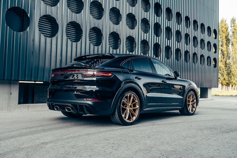 a black porsche cayen is parked in front of a building