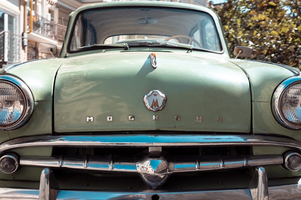 an old green car parked on the side of the road