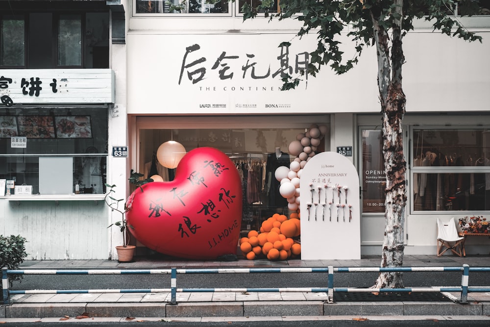 a large heart shaped balloon sitting in front of a store