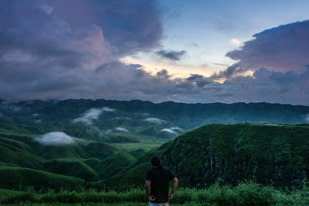 a man standing on top of a lush green hillside