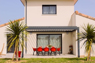 a white house with a red table and chairs