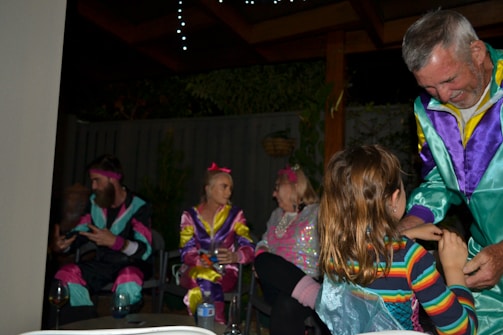 A lively group of friends dressed in 70s retro attire raising drinks during a scavenger hunt bar crawl.