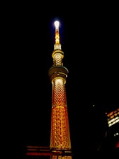 A 7-meter tall navy blue solar lighting tower shining bright white light over a dark construction site at night.