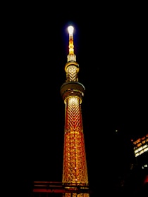 A 7-meter tall navy blue solar lighting tower shining bright white light over a dark construction site at night.