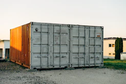 A modern 20ft container painted in sleek grey with the krc gmbh logo, set against a construction site background.