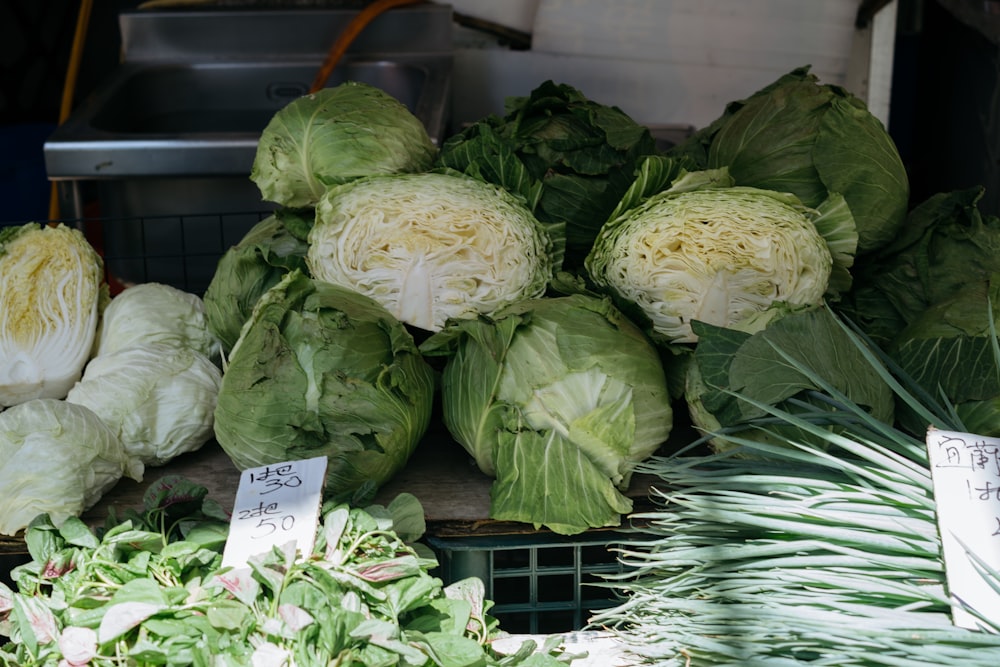 cabbages and other vegetables are on display at a market