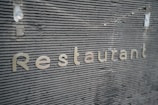 Close-up of shiny stainless steel raised letters installed on a storefront wall in an industrial workshop setting
