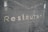 Metallic letters spelling 'Restaurant' are embedded against a textured, dark gray surface. The surface features horizontal grooves giving it a modern, industrial look.