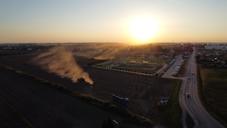 Construction workers leveling ground at a rural road site during sunset.