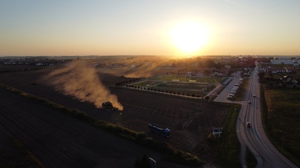 Construction workers leveling ground at a rural road site during sunset.