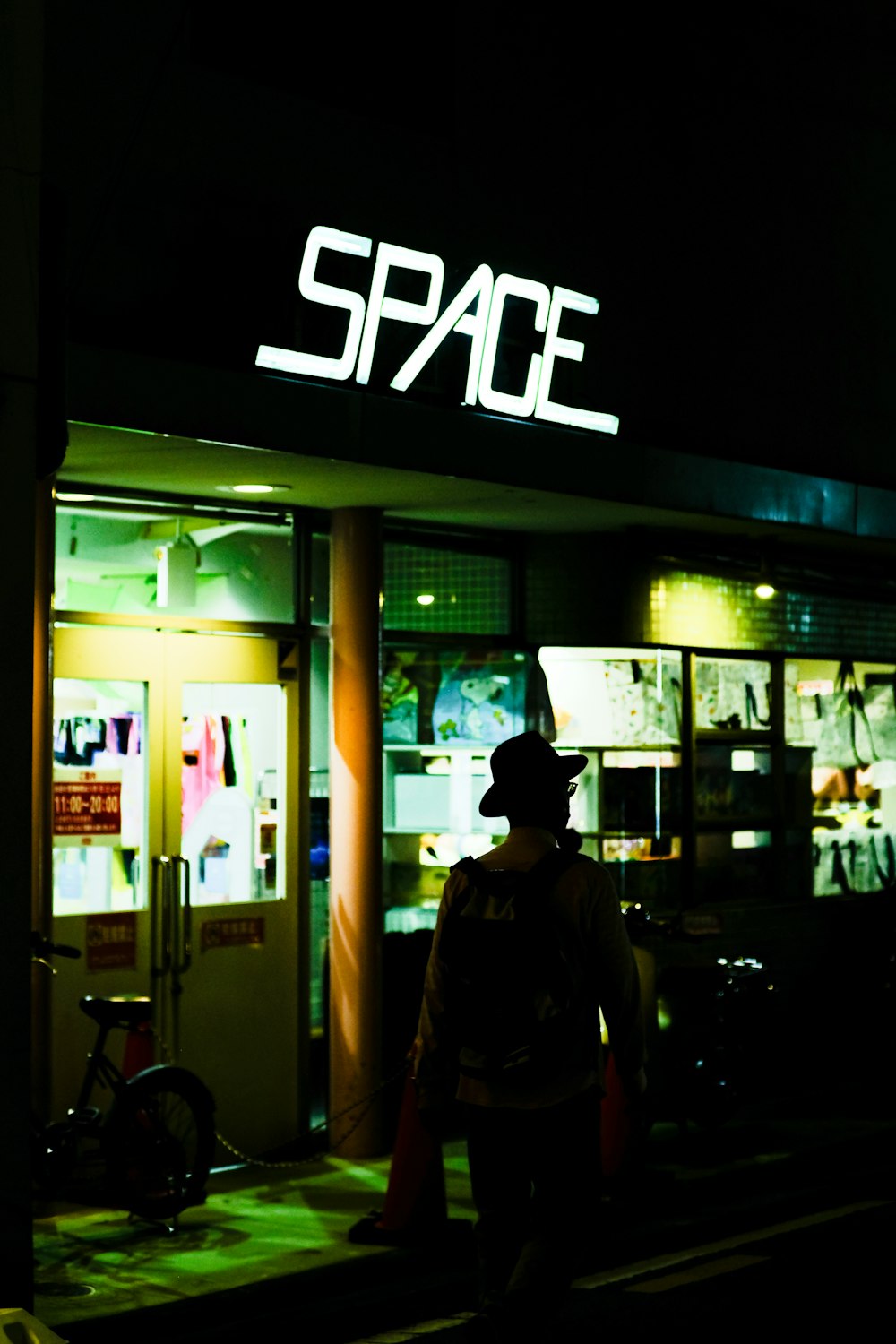 a man standing outside of a space store at night