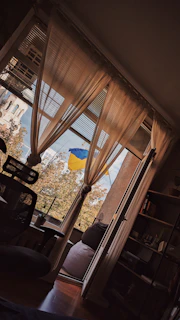 A welcoming office space with a desk, phone, and a small Ukrainian flag beside a window showing Edmonton skyline.