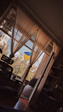 A welcoming office space with a desk, phone, and a small Ukrainian flag beside a window showing Edmonton skyline.