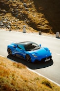 a blue sports car driving down a winding road