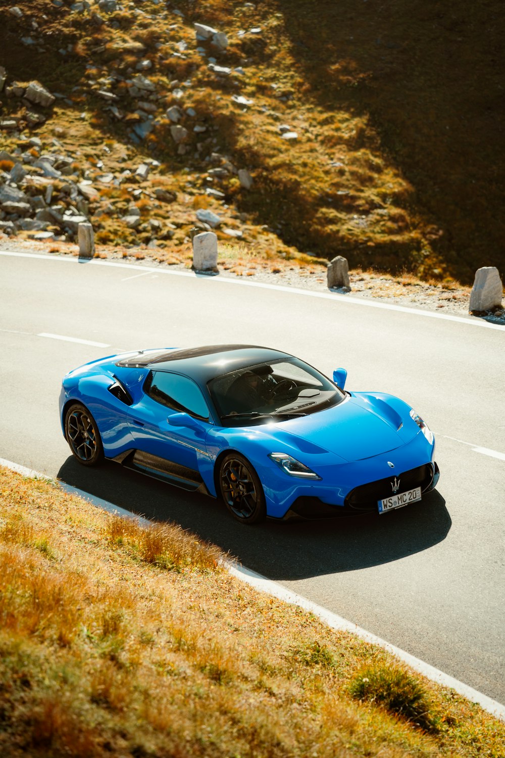 a blue sports car driving down a winding road