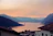 A golden sunset reflecting off Lake Reschen with colorful village rooftops in the foreground.