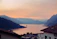 A golden sunset reflecting off Lake Reschen with colorful village rooftops in the foreground.