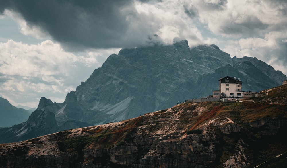 uma casa sentada no topo de uma montanha sob um céu nublado