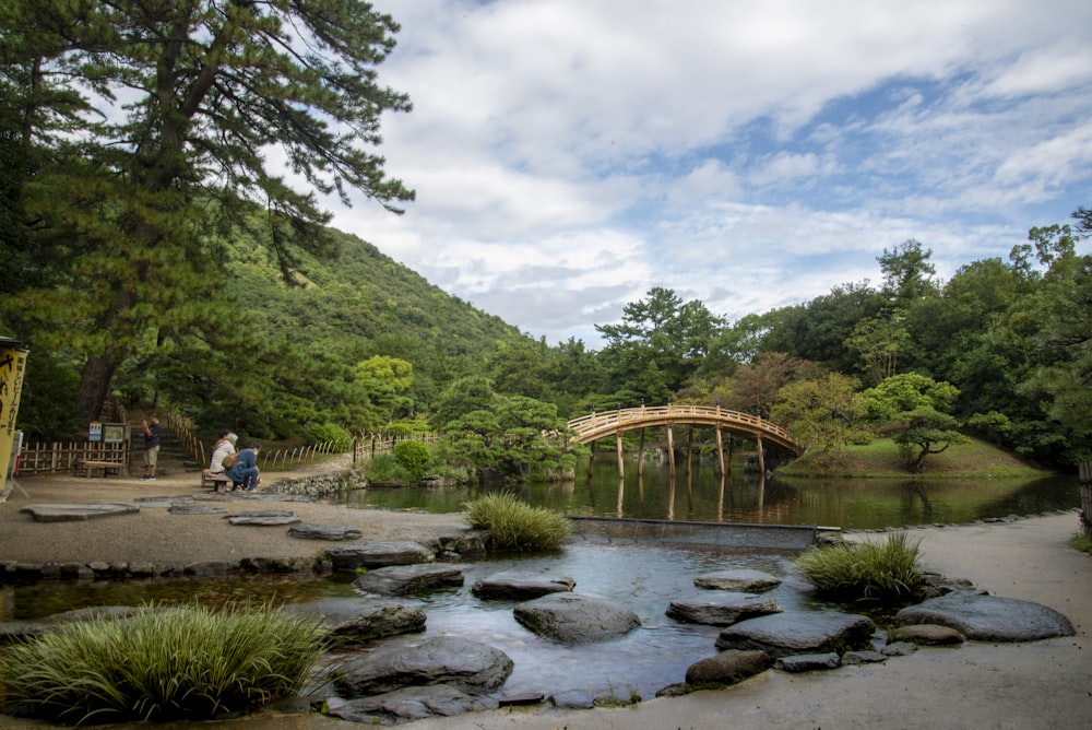 a couple of people walking across a bridge over a river