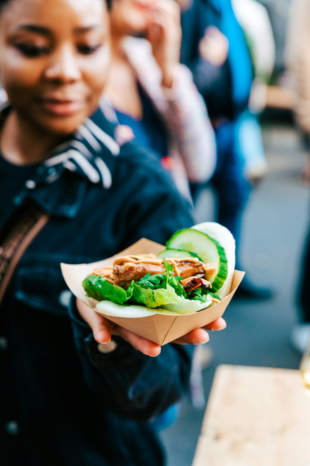 a woman holding a sandwich with lettuce and meat