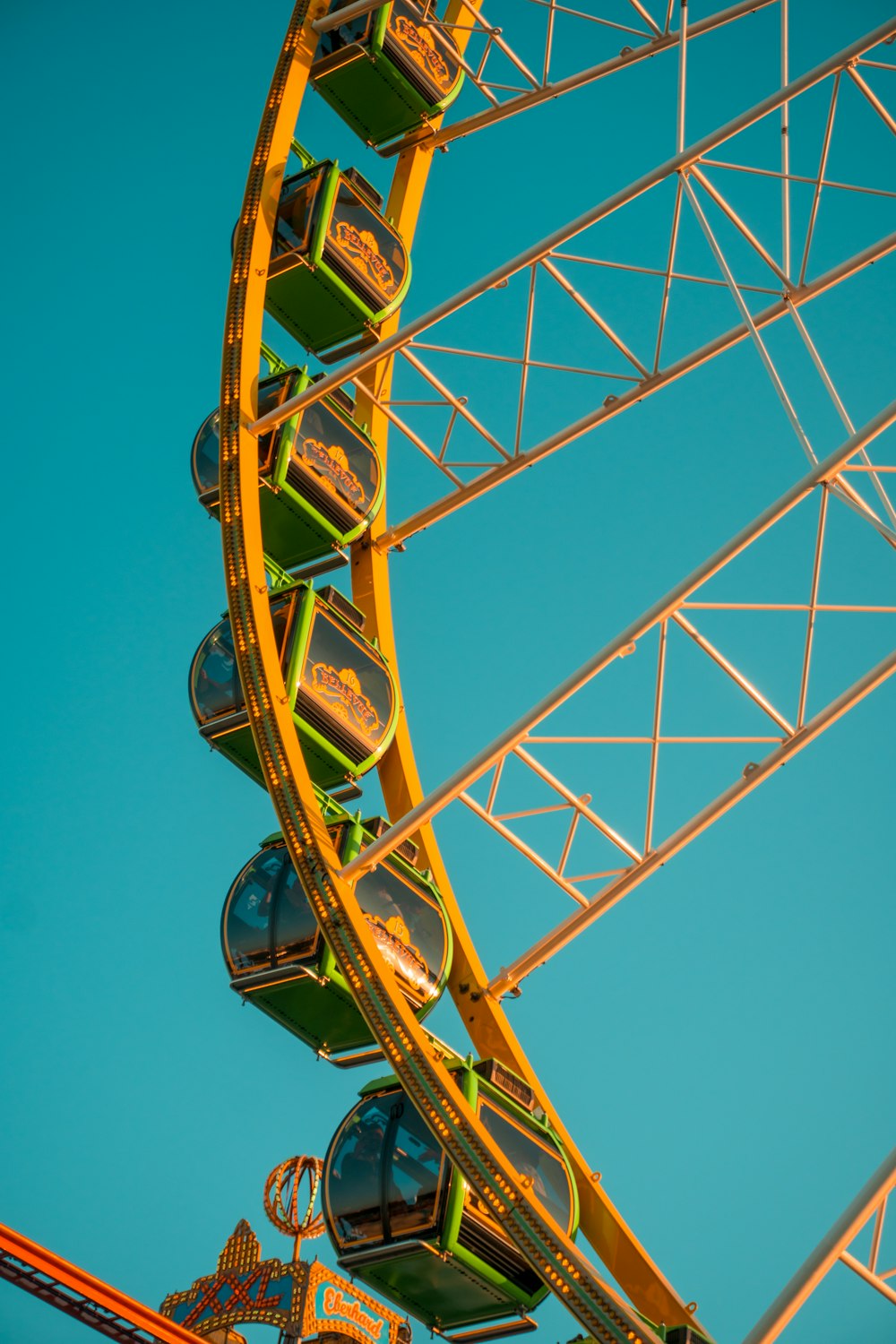 a yellow and green ferris wheel against a blue sky