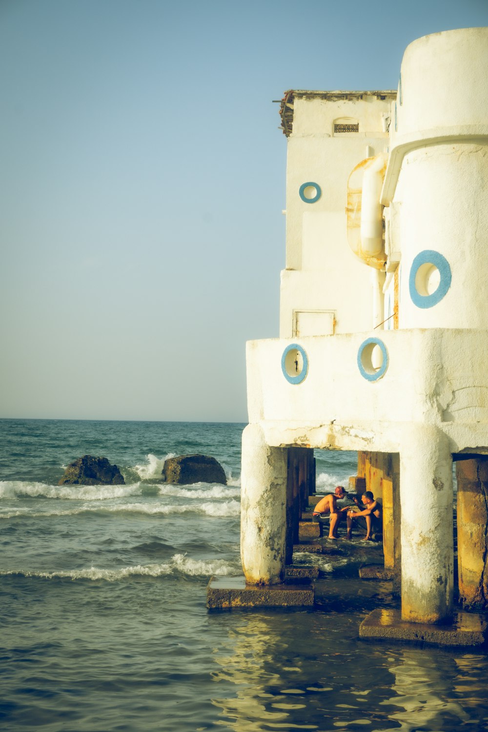 a couple of people sitting on a bench near the ocean