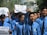 A group of young men wearing blue shirts and black ties are participating in a protest. Some are holding up signs with messages demanding justice and peace. The mood is assertive and determined.