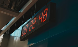 Durable electric clock with bright red LED numbers installed in a manufacturing plant.