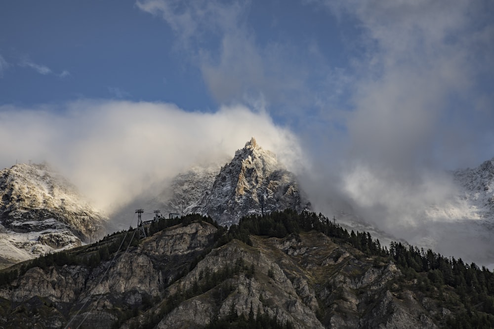 a mountain covered in snow and clouds under a blue sky