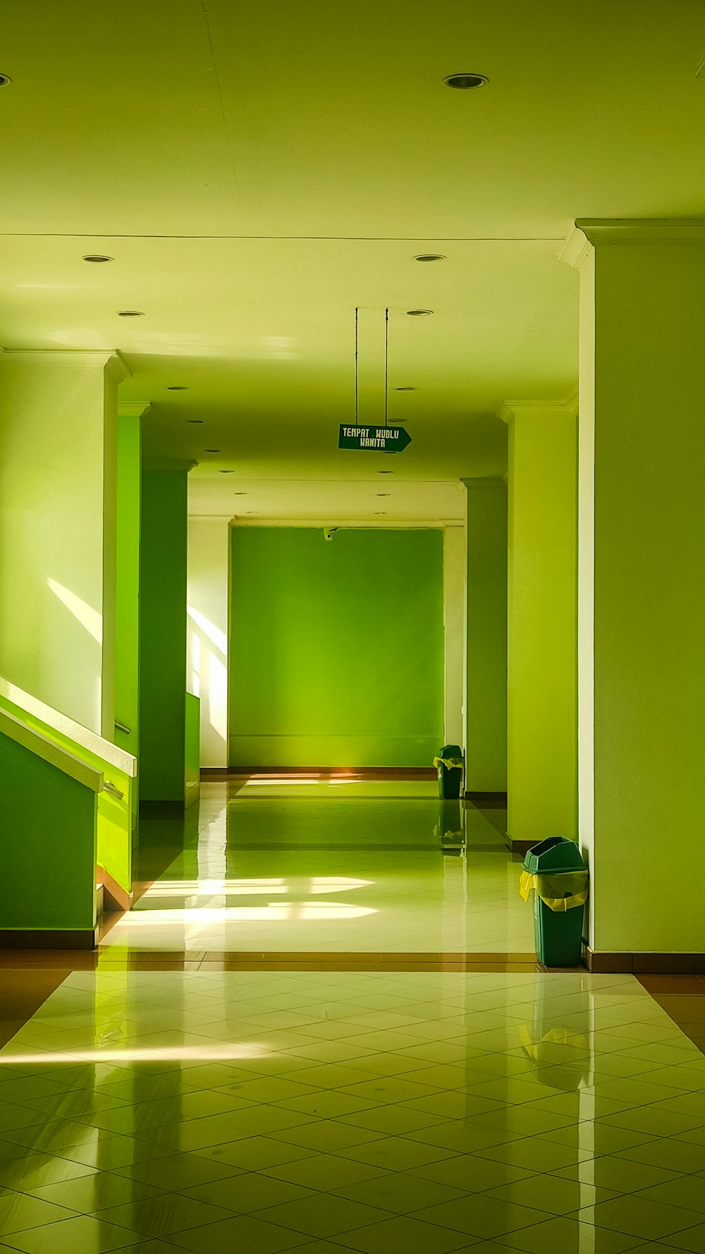 a long hallway with a green wall and a green trash can