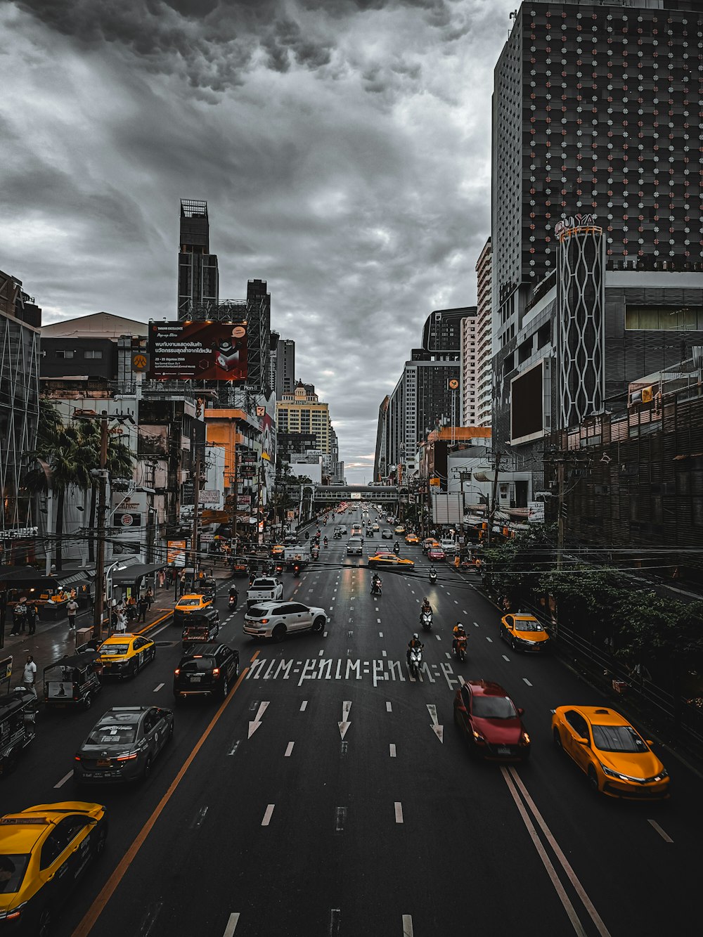 a city street filled with lots of traffic under a cloudy sky