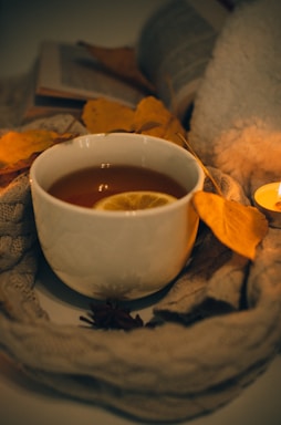 A cozy scarf draped over a wooden table next to a steaming cup of tea and a handwritten note.