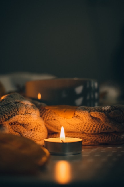 Close-up of a cozy corner featuring soft blankets and a flickering candle