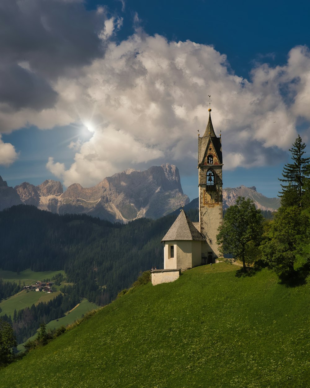 eine Kirche auf einem Hügel mit Bergen im Hintergrund