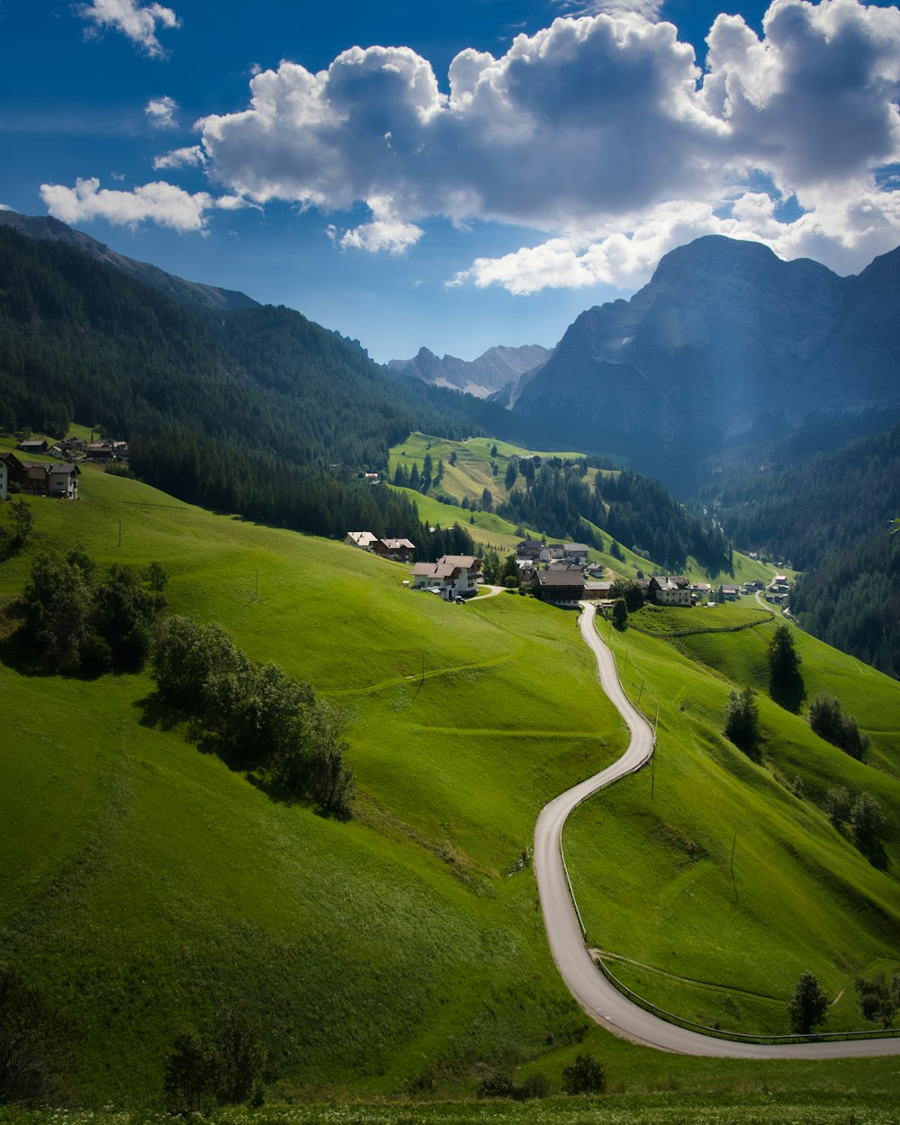 a winding road in the middle of a lush green valley