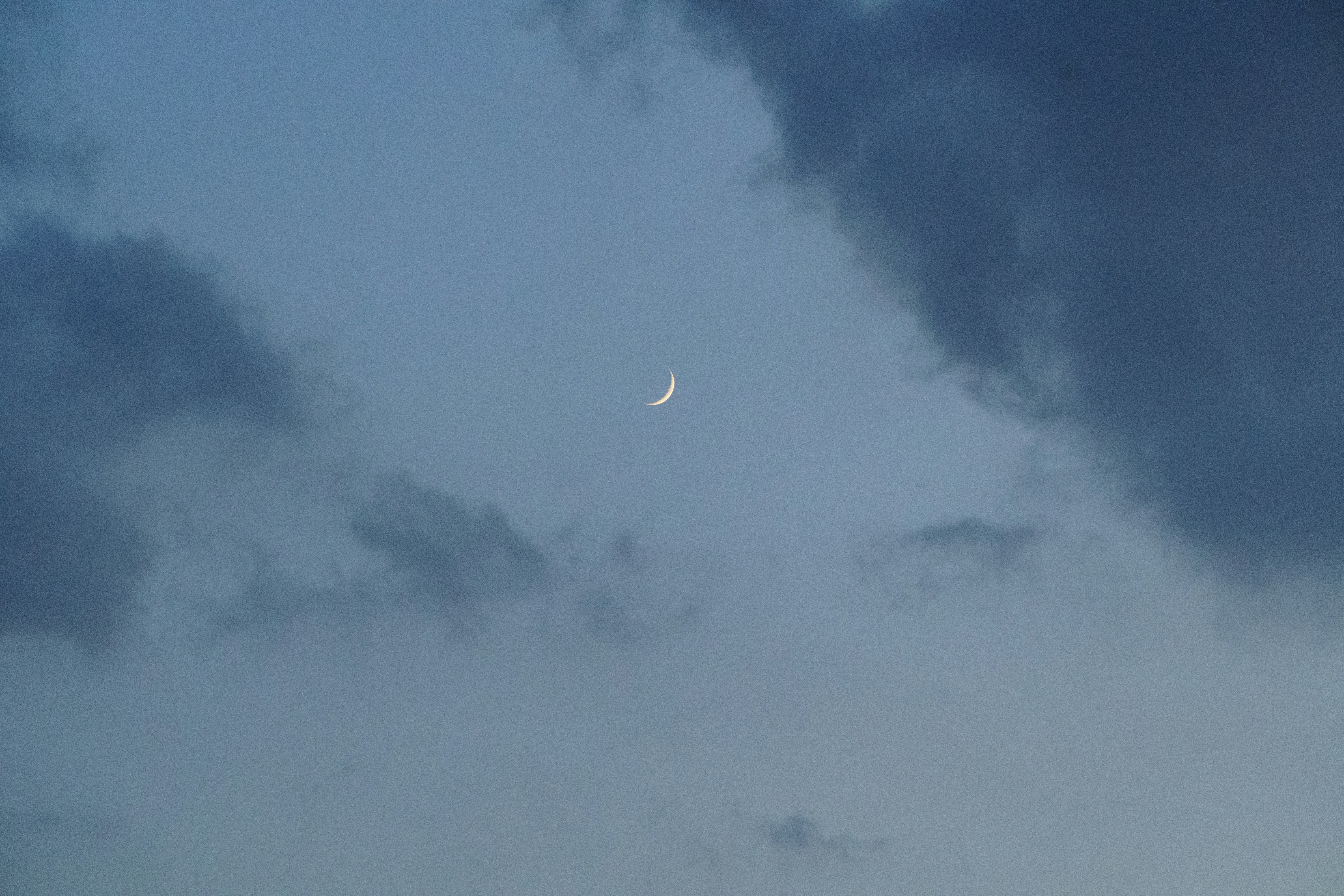 the moon is seen through the clouds in the sky