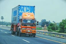 A modern orange and black truck on a highway at sunset, symbolizing reliable cargo transport.