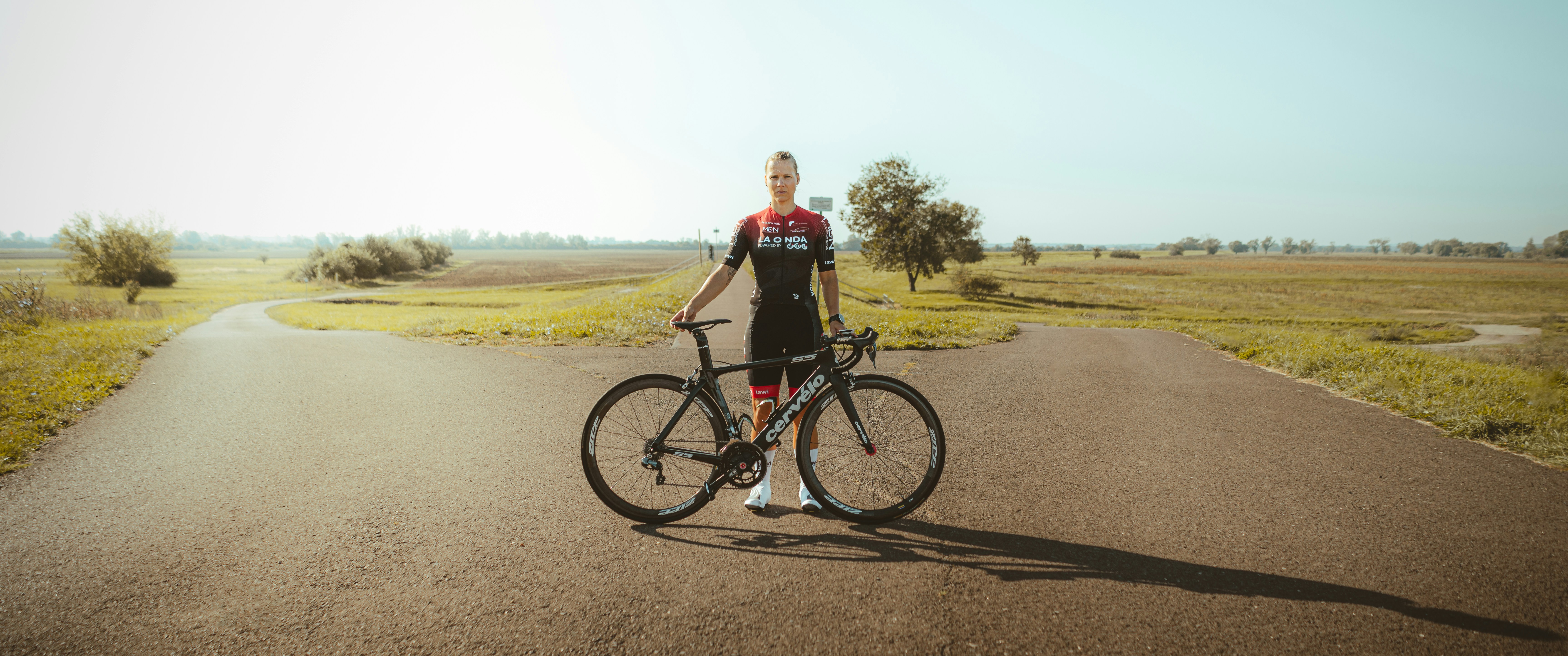 a woman standing next to a bike on a road