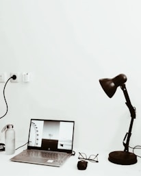 A minimalist workspace with a charcoal grey camera bag and a laptop displaying a photo editing software.