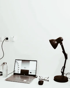 A minimalist modern workspace with a laptop displaying a photography portfolio on screen.