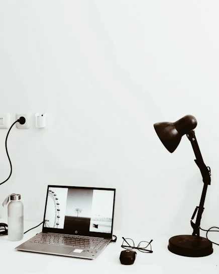 A minimalist modern workspace with a laptop displaying a photography portfolio on screen.