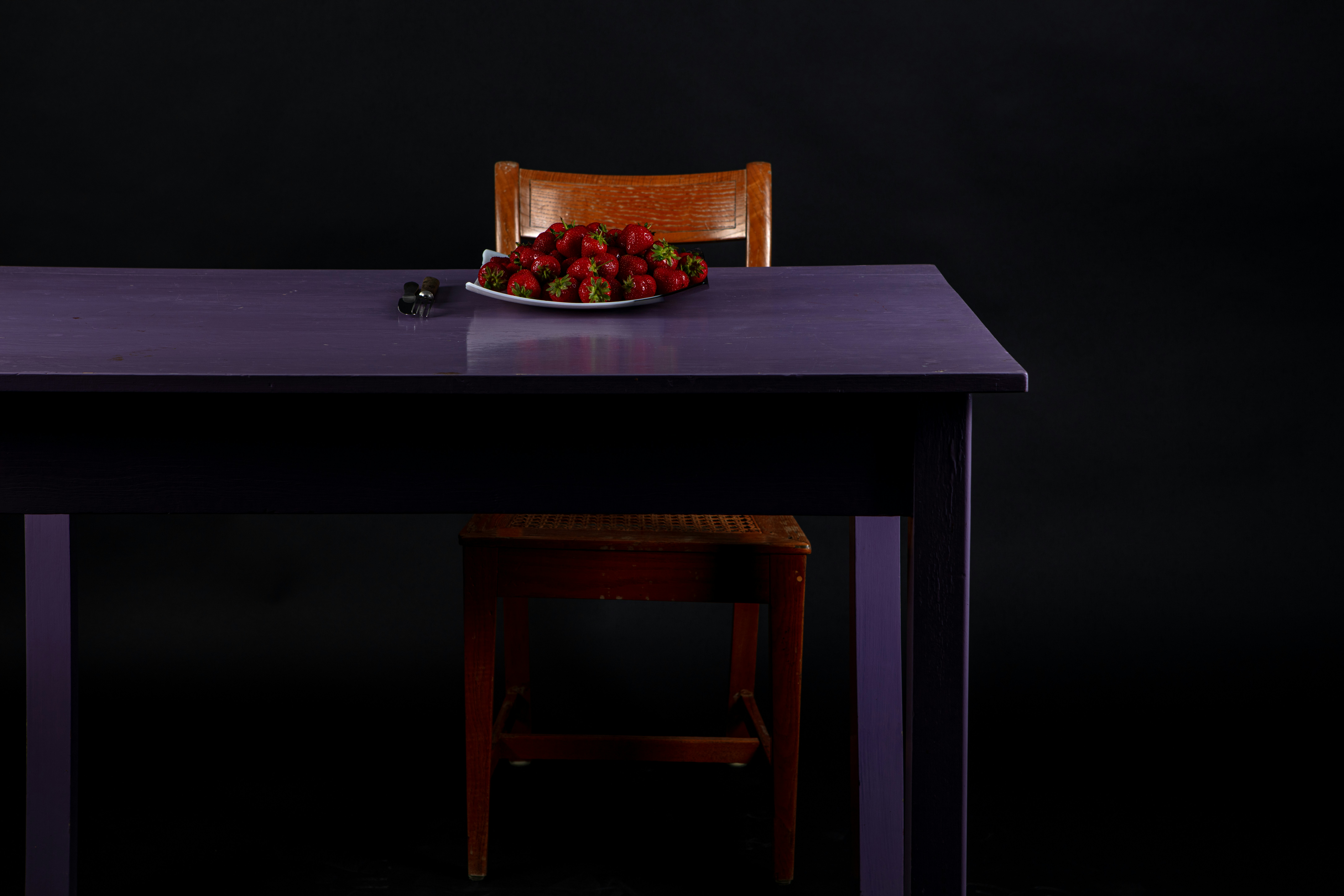 a plate of strawberries on a purple table