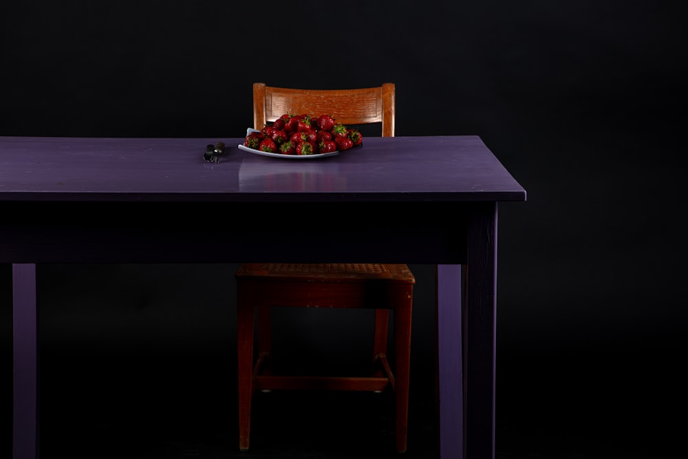 a plate of strawberries on a purple table